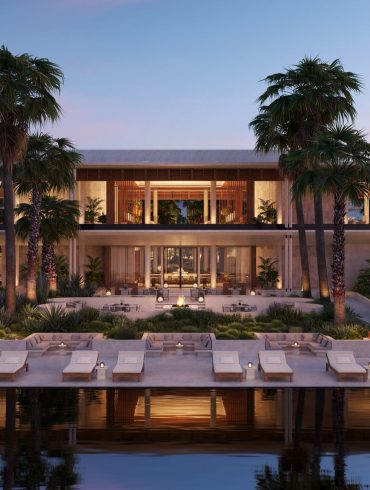 Modern tropical resort with an open-air lounge, palm trees, and poolside seating at dusk.