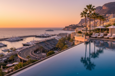Infinity pool overlooking a harbor at sunset, with palm trees, yachts, and a hillside cityscape in the distance.