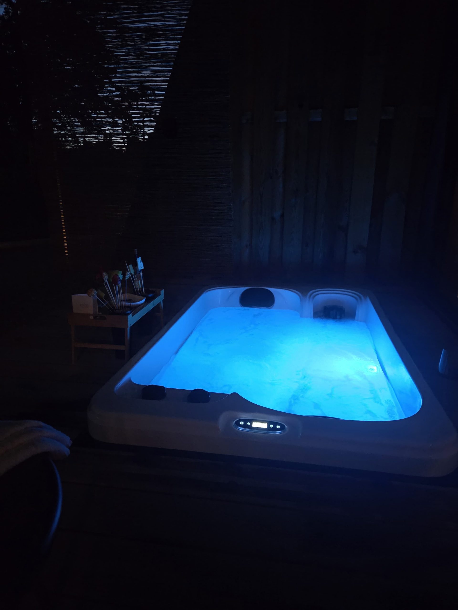 Jacuzzi privatif Pépite Lodge nuit éclairage bleu palissade bambou