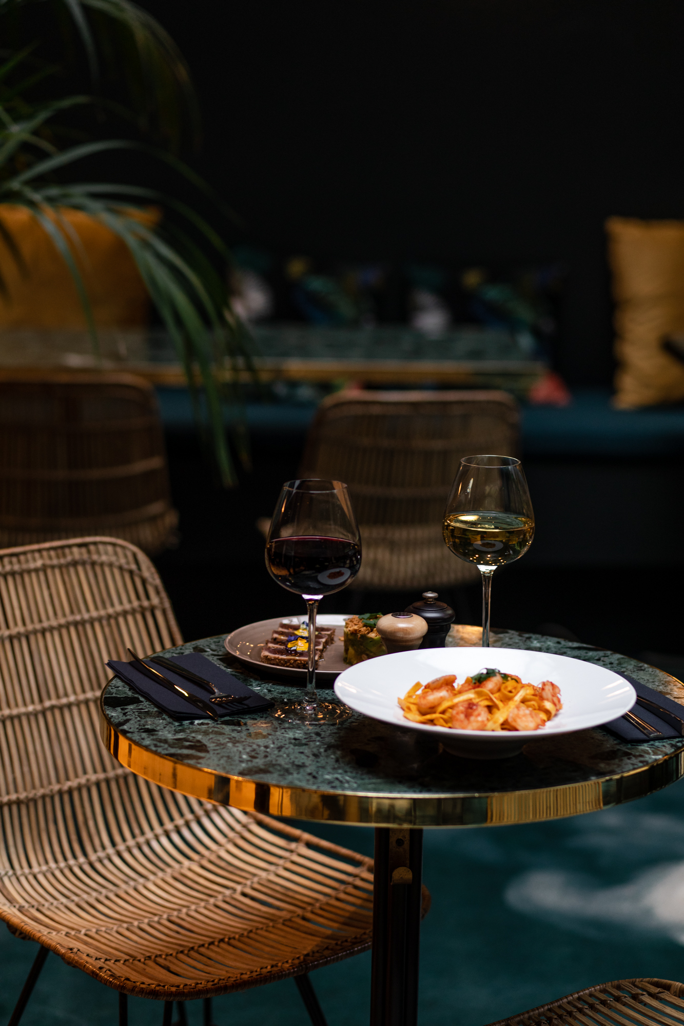 Table pour deux au Parister Hotel : verres de vin et plat de pâtes dans un décor vert velours