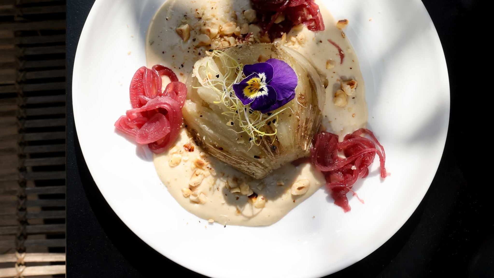 Plat signature du restaurant Les Passerelles au Parister Hotel Paris : fenouil, fleur comestible, oignons rouges, sauce noisette
