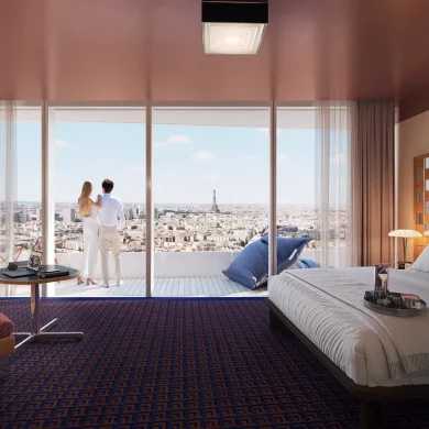 Couple stands on a balcony in a modern hotel room, overlooking a city skyline with the Eiffel Tower in the distance.