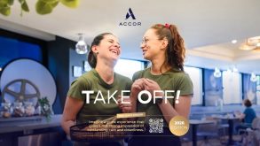 Two smiling women in green shirts share a moment in a modern cafe; ACCOR logo above and 'TAKE OFF!' headline overlaid.