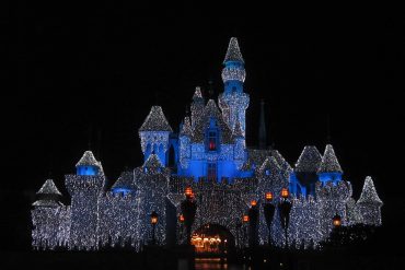 Castle lit with thousands of white Christmas lights at night, glowing against a dark sky.
