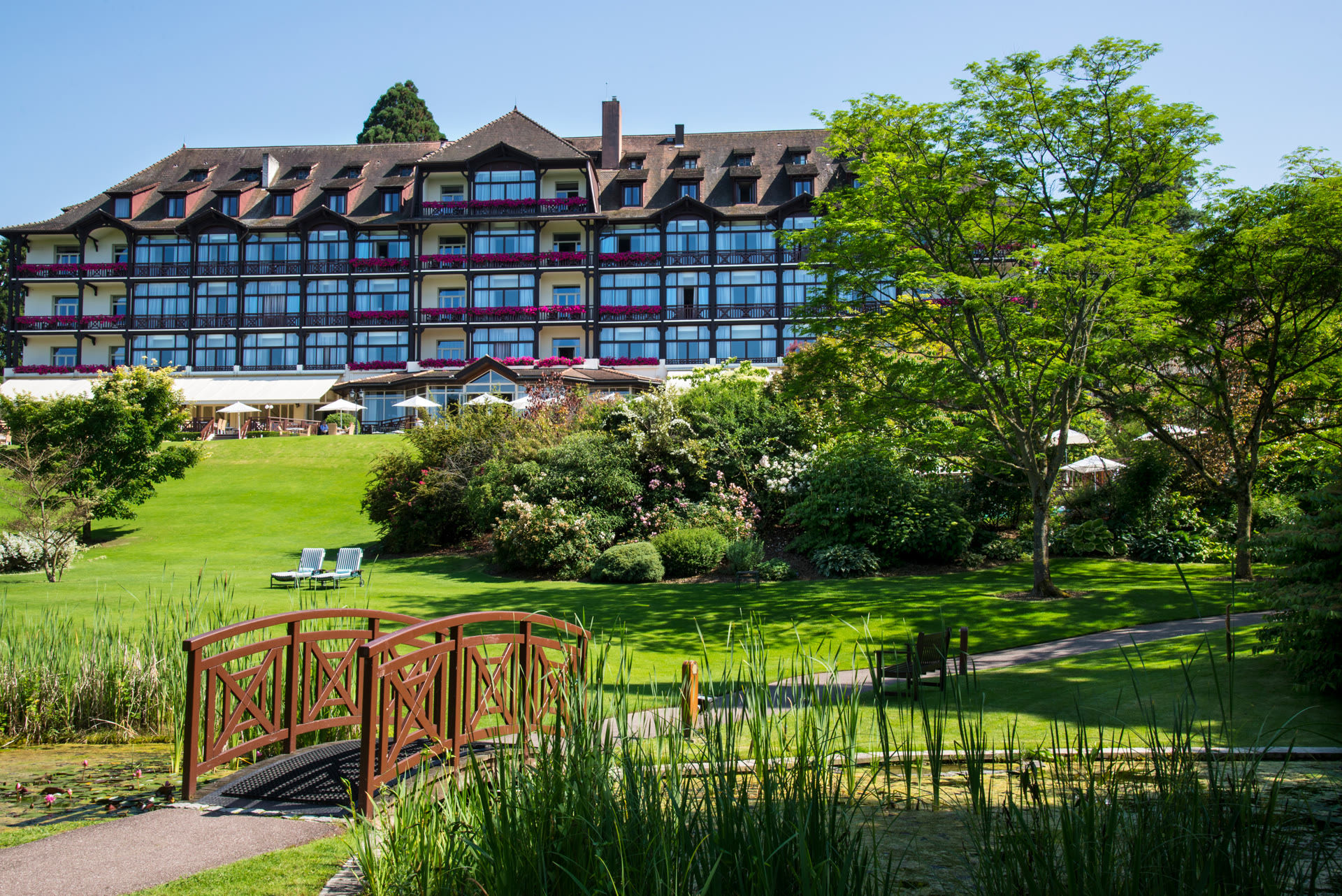 L'Hôtel Ermitage de l'Évian Resort, son jardin et son pont rouge, idéal pour un séjour en famille
