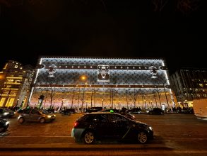 Le 103-111 Champs-Élysées habillé d’une malle Louis Vuitton géante illuminée, la nuit, sur l’avenue.