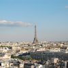 Paris skyline with the Eiffel Tower rising above white rooftops under a clear blue sky, daytime view.