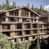 Modern multi-story wooden chalet complex with stone accents in a forested mountain setting