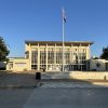 Dallas Skyline High School facade with a tall flagpole and flags against a clear blue sky.