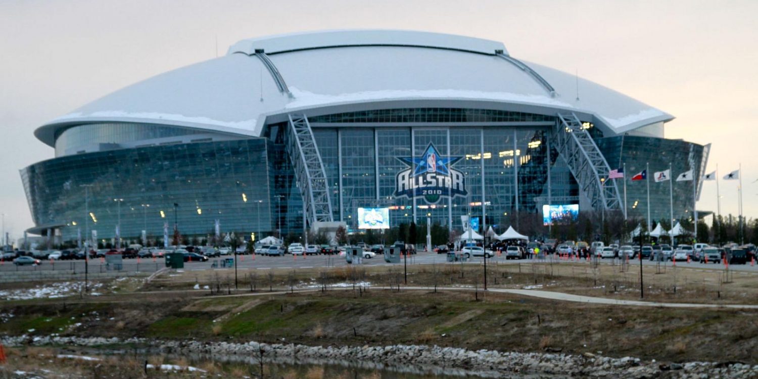 Modern stadium with glass facade and a snow-covered curved roof; NBA All-Star 2010 logo on the front.