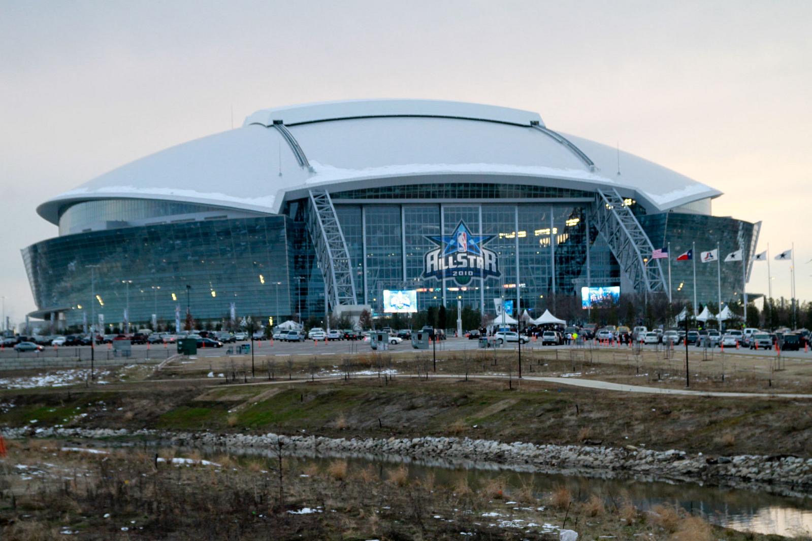 Modern stadium with glass facade and a snow-covered curved roof; NBA All-Star 2010 logo on the front.