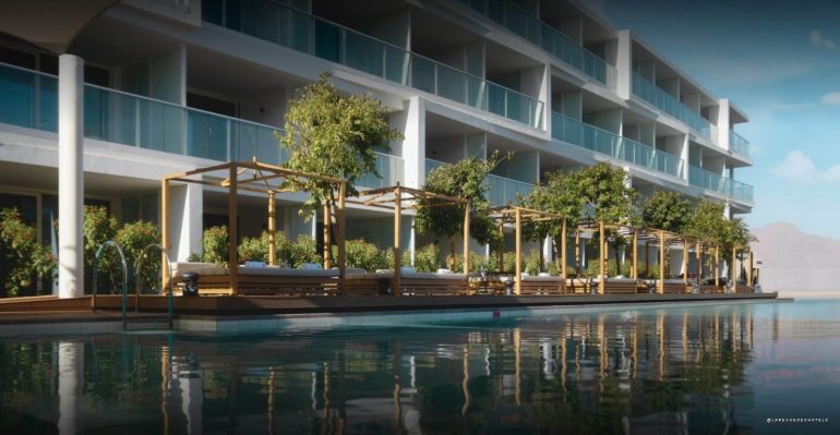Modern hotel with glass balconies and a wooden poolside cabana lounge along a reflective pool in front of the building.