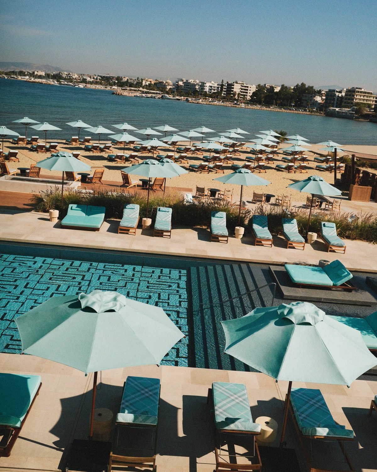 Rangées de transats et parasols au motif House Check turquoise de Burberry sur la plage du One&Only Aesthesis