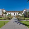 Hotel courtyard with palm trees, green lawn, and white buildings surrounding a central paved walkway.
