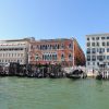 Gondolas docked along a Venetian canal with ornate historic buildings and a blue sky above.