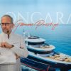 Chef Michel Portos in a white coat with folded arms stands before a blue backdrop featuring a luxury yacht and the text ‘Gamme Prestige’.