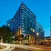 Corner of a modern glass hotel building at dusk with light-trail traffic on the street corner