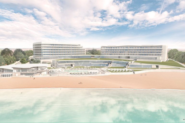 Modern beachfront hotel complex with two curved glass buildings, pool, and sandy shore.
