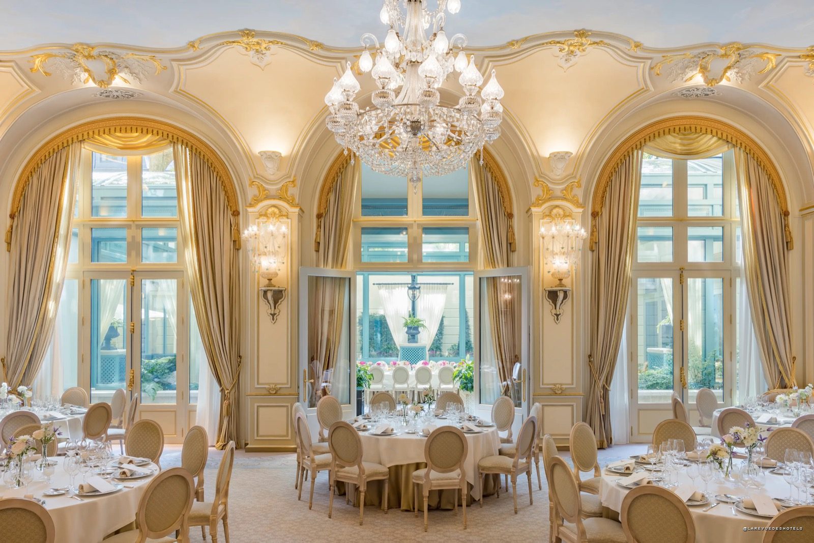 Un salon de réception du Ritz Paris avec lustres et grandes fenêtres sur le jardin