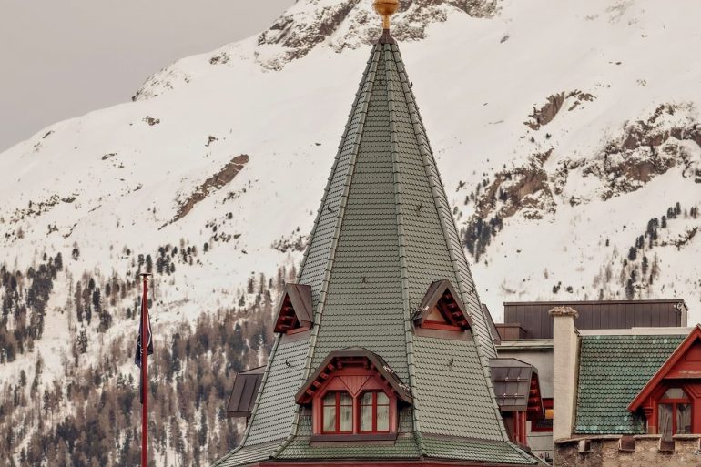 La tour emblématique du Badrutt’s Palace à Saint-Moritz devant les sommets enneigés de l’Engadine