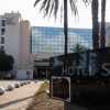 Hotel Sidi exterior with palm trees, glass façade, and a foreground sign reading HOTEL SIDI