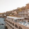 Resort terrace built into a rocky shoreline overlooking the sea with blue couches and white chairs.