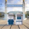 Boîtes de thé Plume de Vanille et Herbes de Provence Maison Gabrielle devant la piscine et la façade de l'Hôtel Martinez à Cannes