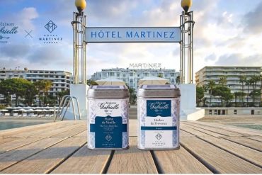Boîtes de thé Plume de Vanille et Herbes de Provence Maison Gabrielle devant la piscine et la façade de l'Hôtel Martinez à Cannes