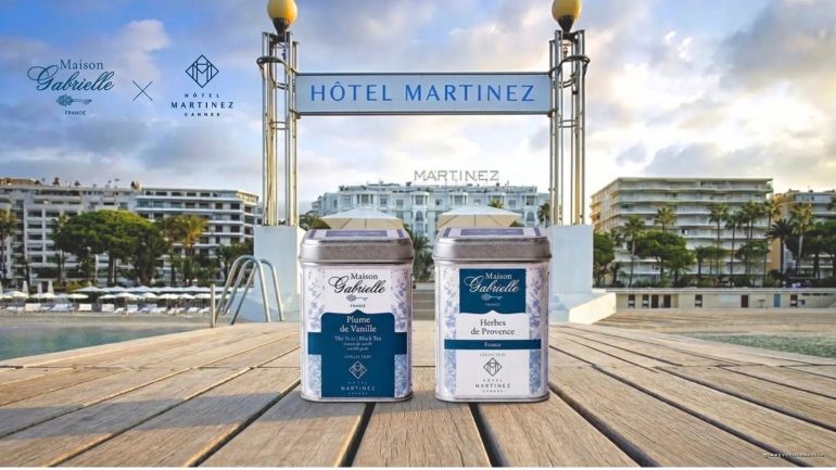 Boîtes de thé Plume de Vanille et Herbes de Provence Maison Gabrielle devant la piscine et la façade de l'Hôtel Martinez à Cannes