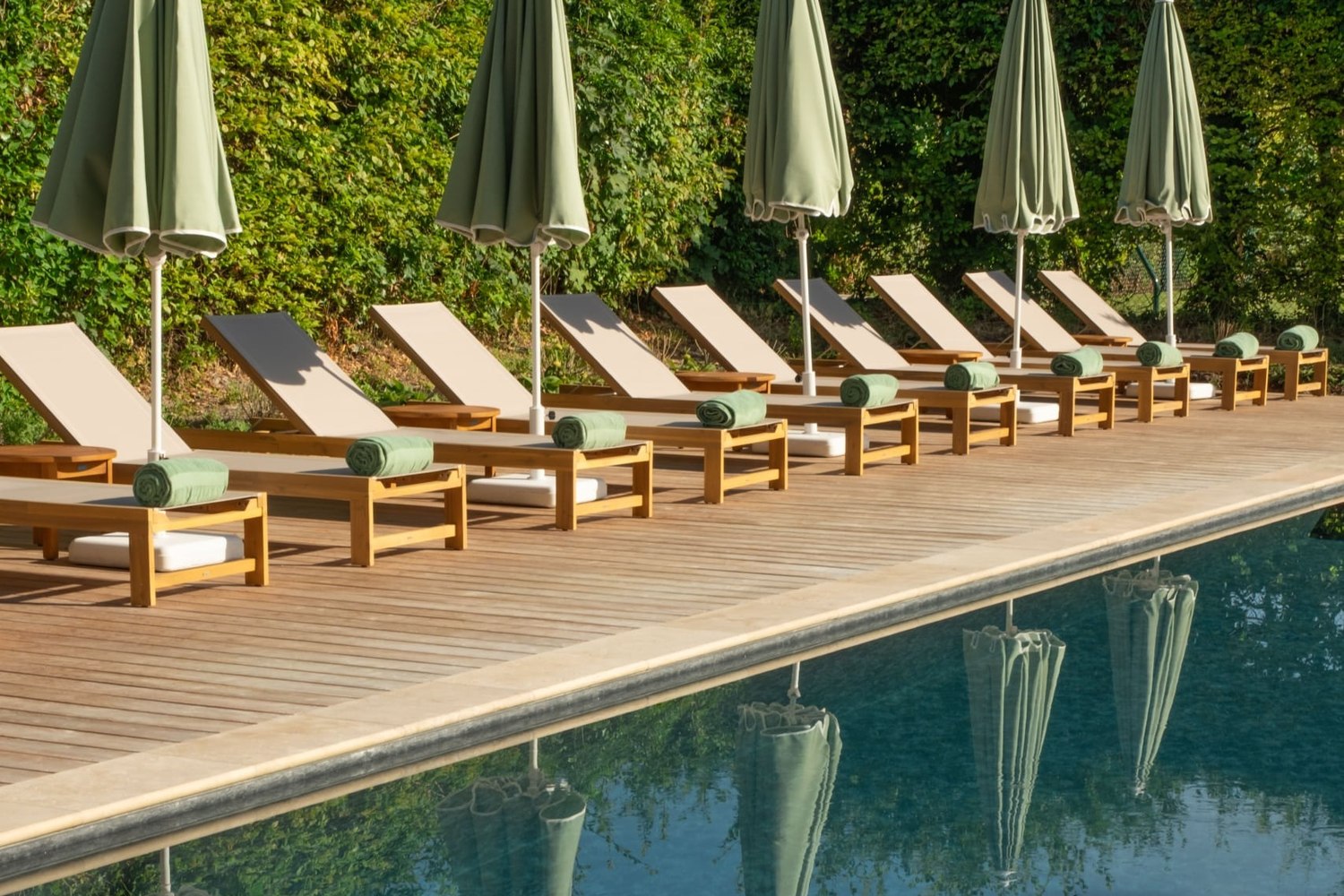 La piscine extérieure des Sources de Vougeot et ses parasols, dans le parc du château
