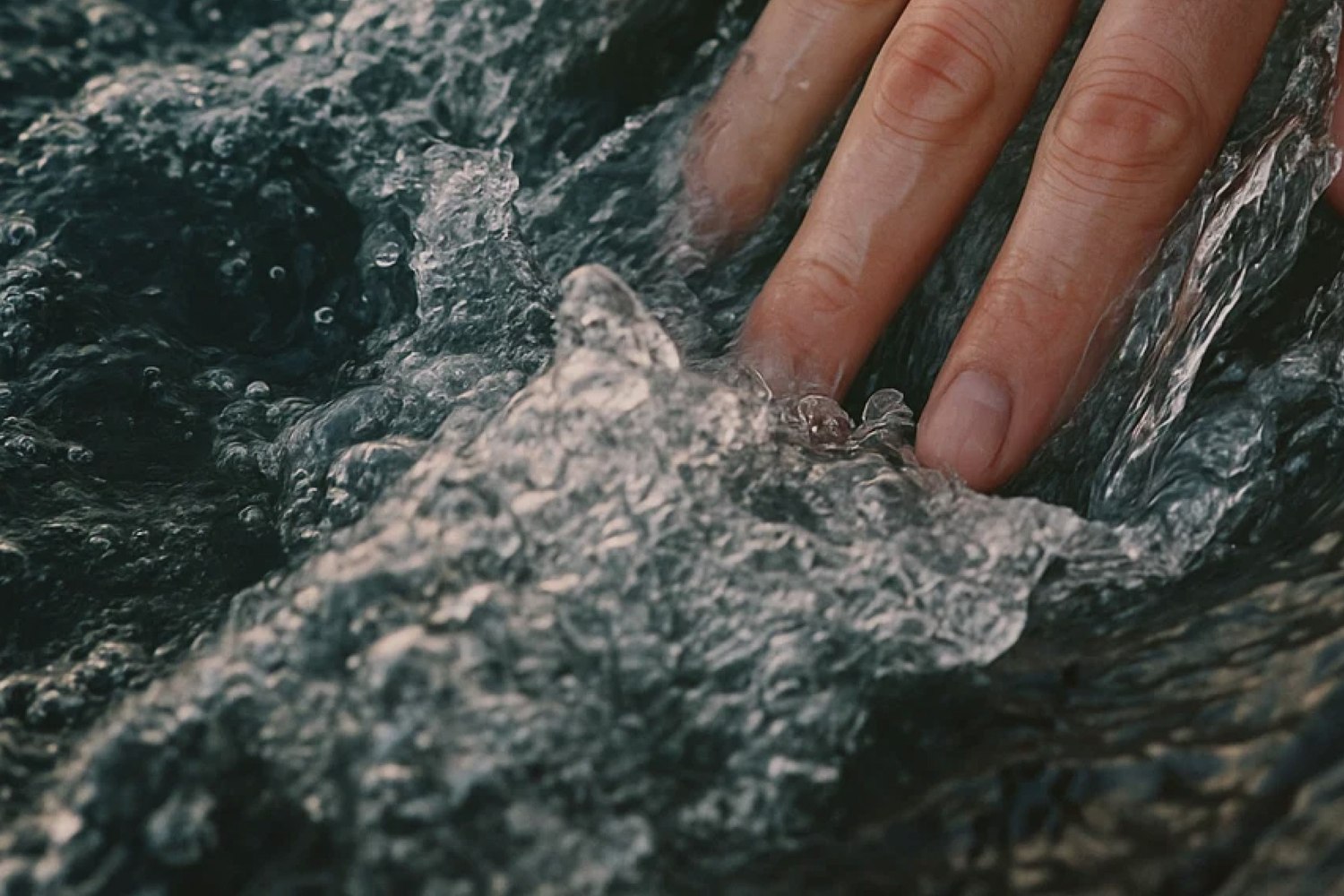 Une main brisant la surface de l'eau chaude à Reykjaböð