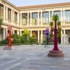 Historic courtyard with a two-story colonnade and bright abstract tree sculptures in red, purple, and orange.