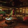 Opulent hotel lounge with leopard-print carpet, plush sofas, and a circular marble coffee table under warm lighting, plus hanging rope swings.