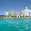 White hotel resort on a sandy beach with palm trees and turquoise sea.