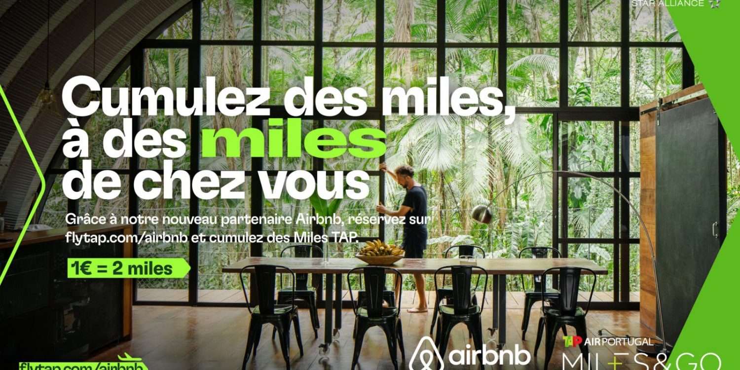 Banner promoting Airbnb Miles: large French headline over a glass-walled tropical dining room; man stands at a long table amid green accents on the sides.