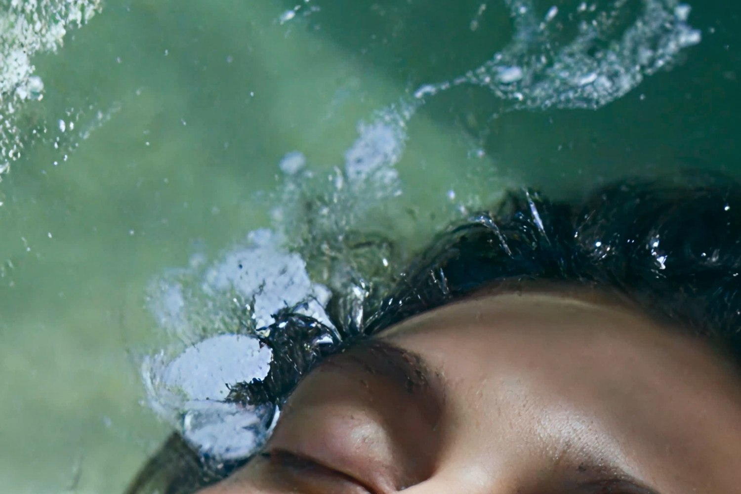 Un visage à la surface de l'eau thermale verte de Reykjaböð