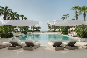 Piscine du Delano Dubai à Bluewaters, parasols et transats sous les palmiers, hôtel Ennismore du groupe Accor à Dubaï