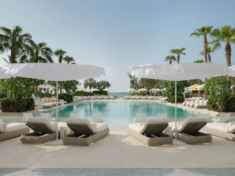 Piscine du Delano Dubai à Bluewaters, parasols et transats sous les palmiers, hôtel Ennismore du groupe Accor à Dubaï