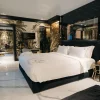 Chambre de la Bra Hotel Spa Suite à Bari, lit king-size noir, marbre blanc et fresque tropicale dorée