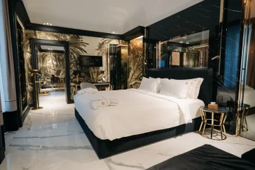 Chambre de la Bra Hotel Spa Suite à Bari, lit king-size noir, marbre blanc et fresque tropicale dorée