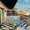 Terrasse d'une chambre de Casa Verbena Madrid, transats en rotin et sol en damier noir et blanc au-dessus des toits de tuiles de Madrid
