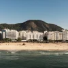La façade blanche du Copacabana Palace, A Belmond Hotel, face à la plage de Copacabana à Rio de Janeiro, les morros en arrière-plan