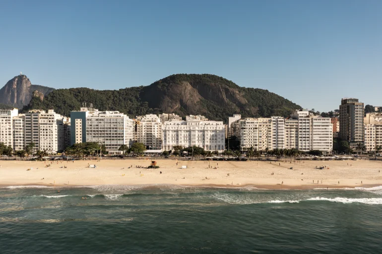 La façade blanche du Copacabana Palace, A Belmond Hotel, face à la plage de Copacabana à Rio de Janeiro, les morros en arrière-plan