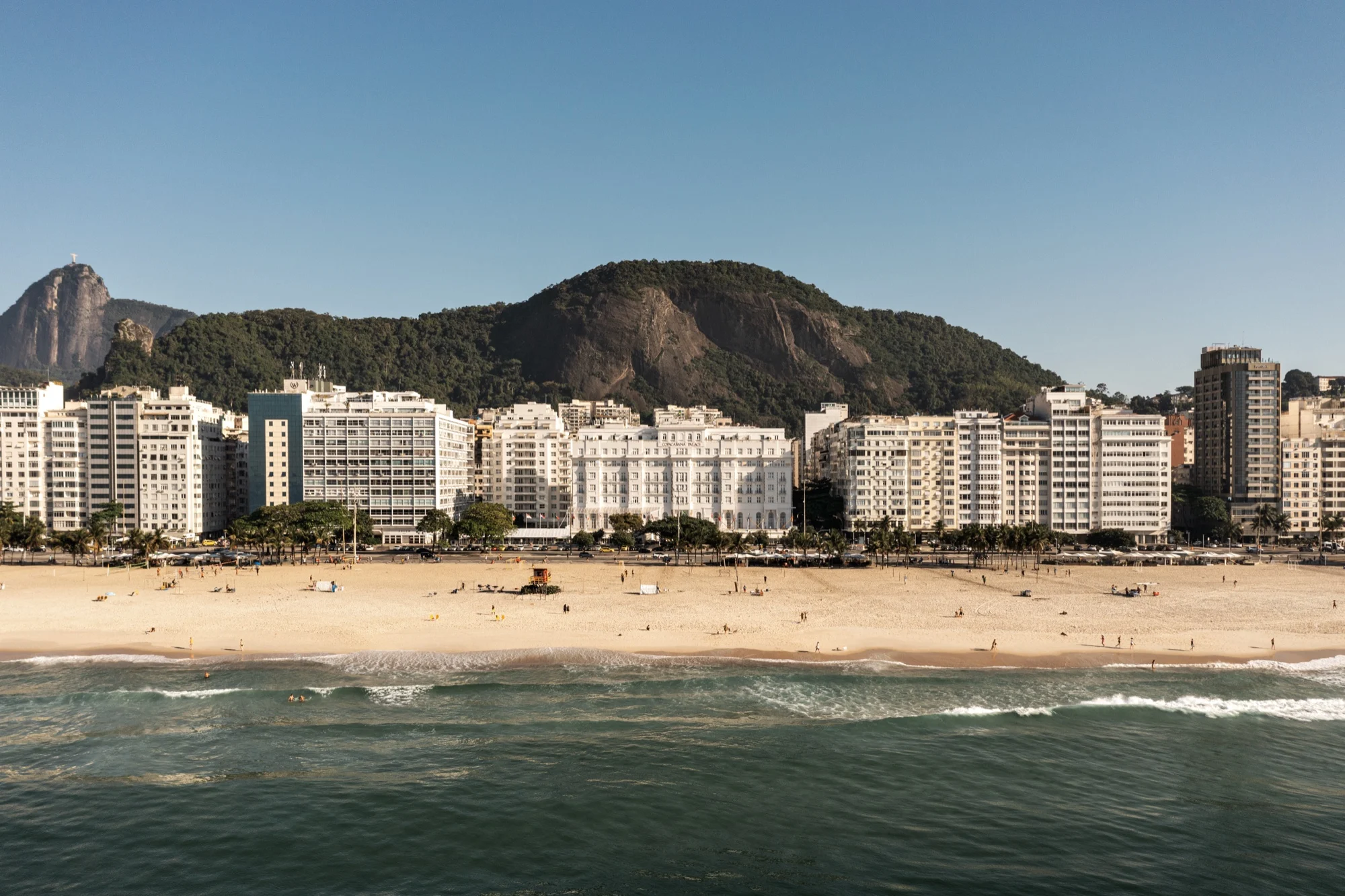 La façade blanche du Copacabana Palace, A Belmond Hotel, face à la plage de Copacabana à Rio de Janeiro, les morros en arrière-plan