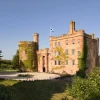 Façade en grès rouge du Dalhousie Castle, château-hôtel près d'Édimbourg, avec sa tour ronde et le drapeau écossais