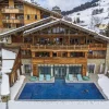 Le Four Seasons Resort Megève sous la neige et sa piscine extérieure chauffée