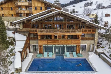 Le Four Seasons Resort Megève sous la neige et sa piscine extérieure chauffée
