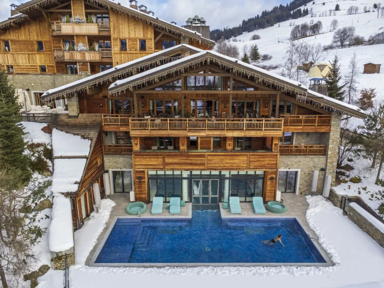 Le Four Seasons Resort Megève sous la neige et sa piscine extérieure chauffée