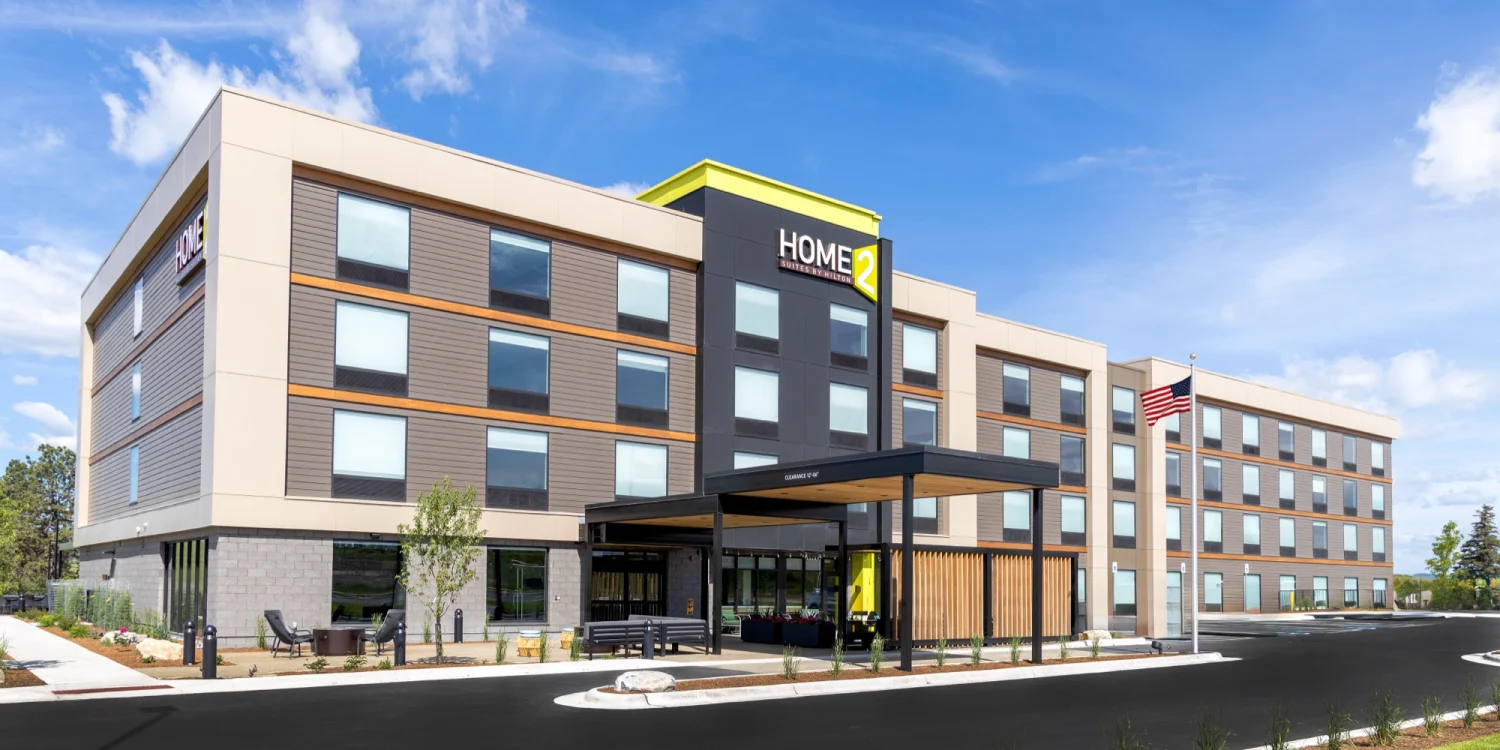 Façade d’un hôtel Home2 Suites by Hilton de quatre étages sous un ciel bleu, prototype Clean Energy