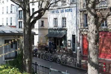 Façade de l'Hôtel du Nord, 102 quai de Jemmapes à Paris, terrasse au store rouge et vélos sur le canal Saint-Martin